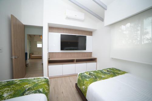 a bedroom with a flat screen tv on a wall at Hotel Barranqueros Soledén in Armenia