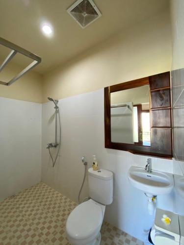 a bathroom with a toilet and a sink and a mirror at Semilir Inn Senggigi in Senggigi 