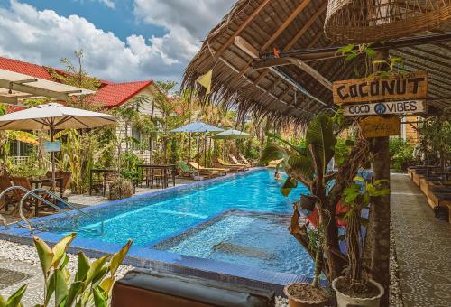 a swimming pool in a resort with an umbrella at Yellow Star Hostel in Kampot