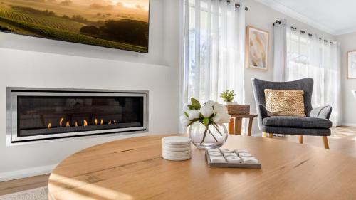 a living room with a table and a fireplace at D'Vine Cottage in Pokolbin