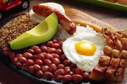 un plato de desayuno con huevos tocino y nueces en Hotel boutique San Pablo en Medellín