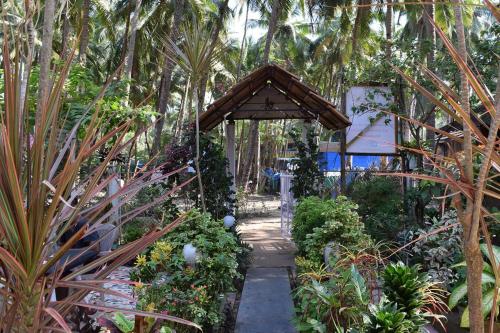 a garden with a wooden arch in the middle at Zappia Cove Resort Palolem in Palolem
