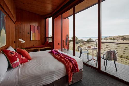 a bedroom with a bed and a balcony with windows at Iron Creek Bay Estate in Sorell