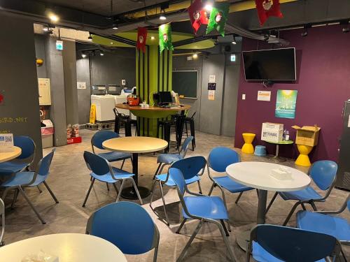 a room with tables and chairs and a tv at Backpackers Hostel - Ximen in Taipei