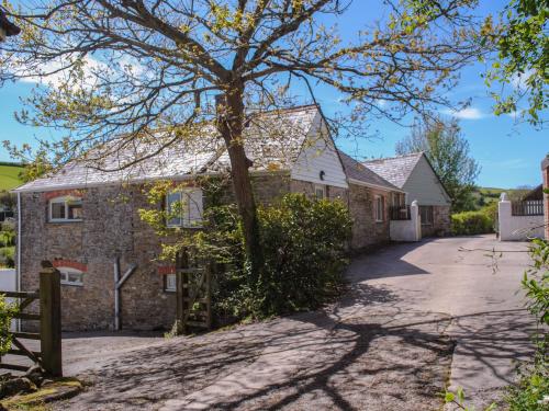 a stone house with a tree in the driveway at Orchard Barn in Salcombe