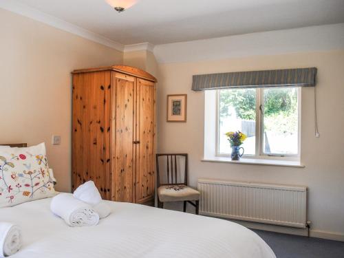 1 dormitorio con cama blanca y ventana en Orchard Barn en Salcombe