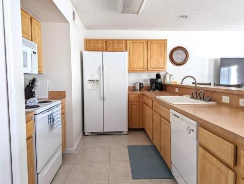 a kitchen with a white refrigerator and wooden cabinets at Be A Nomad - Lovely Neptune Beach 2bed, Monthly in Neptune Beach