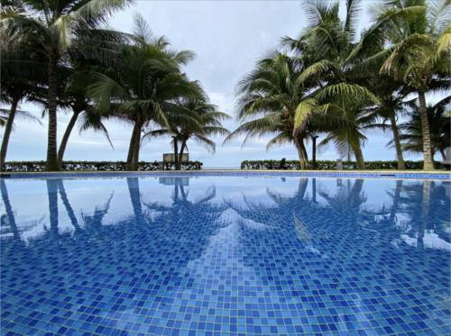 a blue swimming pool with palm trees in the background at Agradable estancia en Monterrico in Monterrico