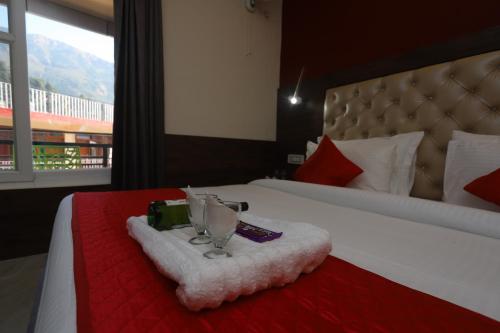 a hotel room with a bed with a red and white bedspread at Hotel Grand Nest in Dharamshala