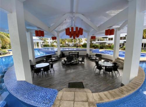 a resort with a pool and tables and chairs at Agradable estancia en Monterrico in Monterrico