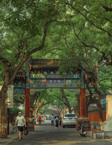 a gate in a street with trees and people walking at Jingfang Building Boutique Smart Hotel - near Beijing Tiananmen Square,the Forbidden City,Wangfujing Street in Beijing