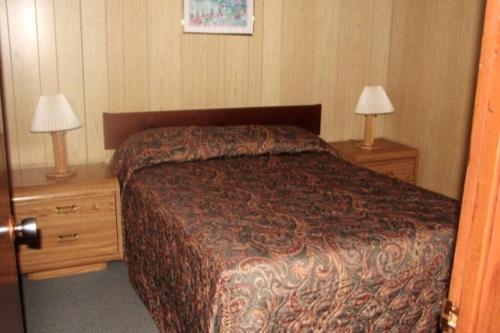 a bedroom with a bed and two night stands with lamps at Betula Lake Resort in Seven Sister Falls