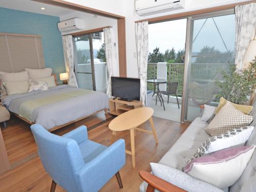 ein Schlafzimmer mit einem Bett, einem Sofa und einem TV in der Unterkunft Churaumi Terrace in Motobu
