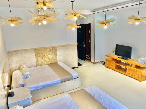 a bedroom with a bed and a television and chandeliers at ZoZo House - Homestay Bai Sau 77 in Vung Tau