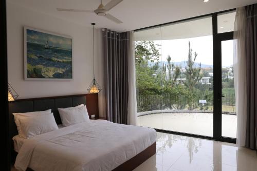 Ivory Villa & Resort في Hòa Bình: غرفة نوم بسرير ونافذة زجاجية كبيرة