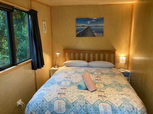 1 dormitorio con 1 cama grande y 2 almohadas en Kiwi cabin with geothermal pool by lake Taupo en Turangi