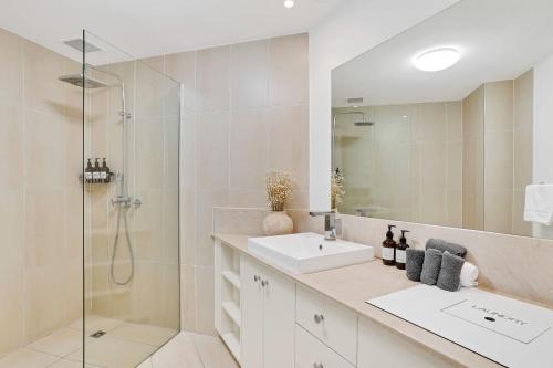ein weißes Badezimmer mit Waschbecken und Dusche in der Unterkunft Lotus Lakes - Resort Style Living in Cairns North