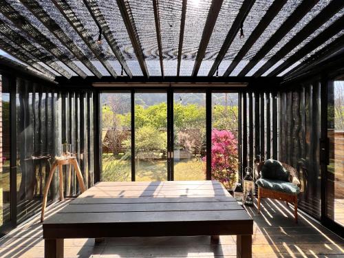 una veranda riparata con tavolo e vista sul giardino di Tiny Base The River HOUSE & TRAILER a Kawazu