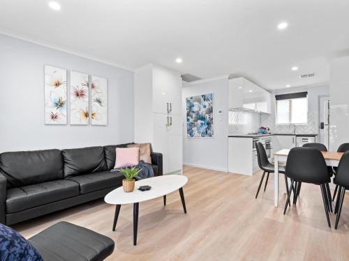a living room with a black couch and a table at Hectorville Luxe Haven Suite in Campbelltown