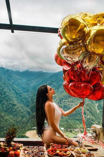 a woman sitting on a table with a bunch of balloons at Eco House Merisi in Merisi
