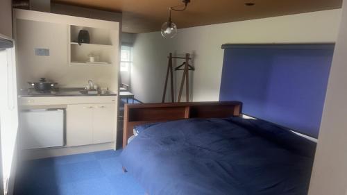 1 dormitorio con 1 cama azul y cocina en WEST in, en Yufu