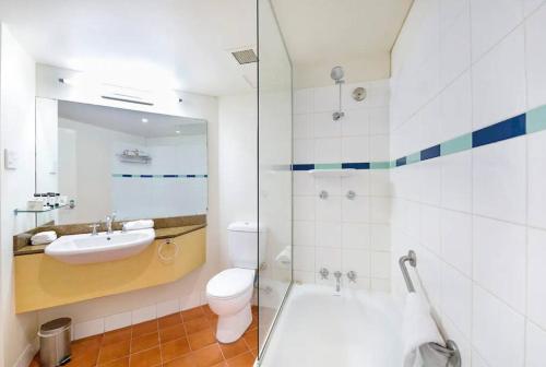 a bathroom with a sink and a toilet and a shower at An Exceptional Seaside Esplanade Locale with Pool in Darwin