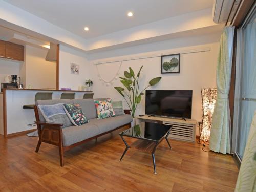 a living room with a couch and a television at Churaumi Terrace in Motobu