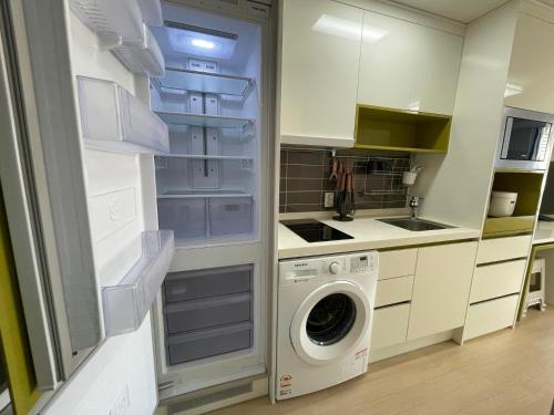 a kitchen with a refrigerator and a washing machine at Joongmoon ocean stay in Seogwipo