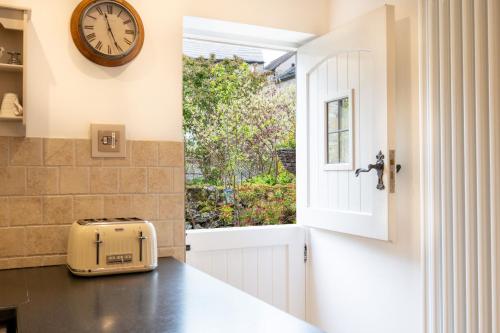 uma cozinha com uma janela e um relógio na parede em Chimney Pots cottage em Youlgreave
