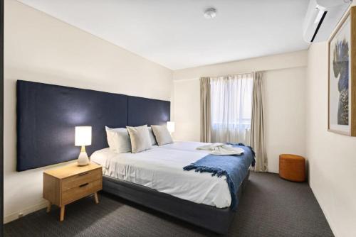 a bedroom with a large bed with a blue headboard at Spacious Holiday Apart on Hay St CBD in Perth