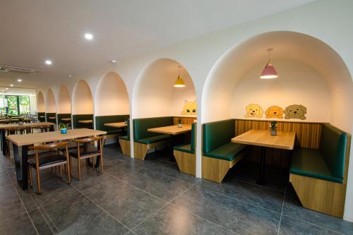een restaurant met houten tafels en groene cabines bij FIRST Studio Hotel in Da Nang