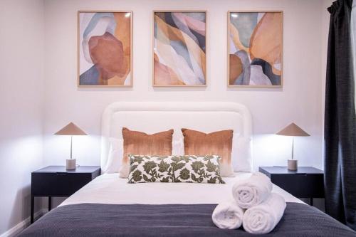 a bedroom with a white bed with two nightstands and two lamps at Stunning Northbridge Townhouse W Off St Parking in Perth