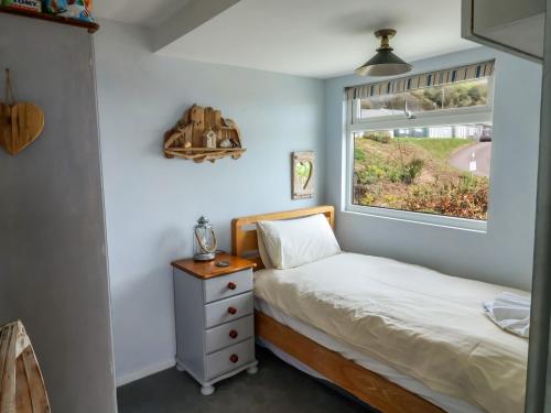 a small bedroom with a bed and a window at Ammonite in Lyme Regis