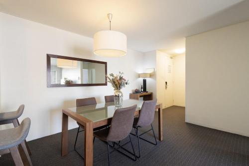 a dining room with a table and chairs and a mirror at East Perth CBD Apartment close to The Swan River in Perth