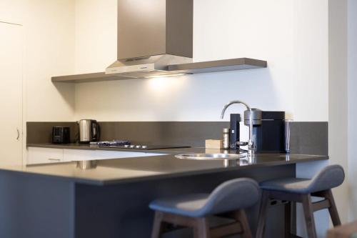 a kitchen with two chairs and a counter with a sink at East Perth CBD Apartment close to The Swan River in Perth