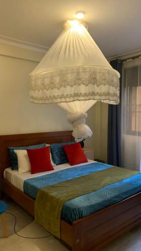 - une chambre avec un grand lit et une lampe dans l'établissement Haz Furnished Apartments Buwate, à Kampala