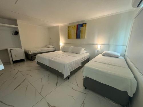 a hotel room with two beds and a bathroom at Pousada Oceanic in Arraial do Cabo