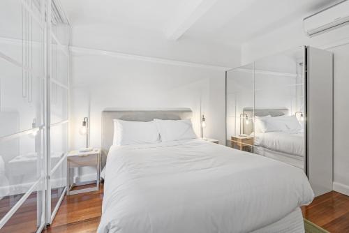 a white bedroom with a large bed and a mirror at Elegant 1-Bed CBD Apartment with Sunroom Study in Melbourne