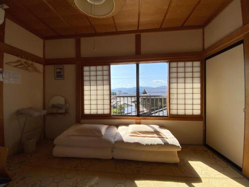 a bedroom with a bed in a room with windows at Guesthouse Takayama Hanzansha in Takayama