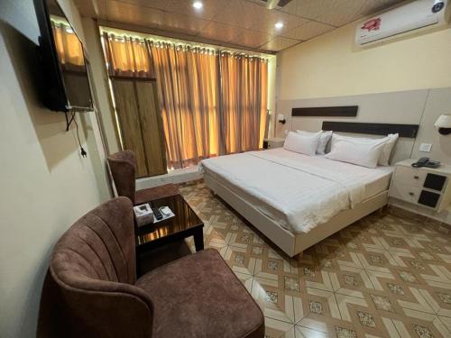 - une chambre avec un lit, une chaise et une télévision dans l'établissement Islamabad Premium Hotel, à Islamabad