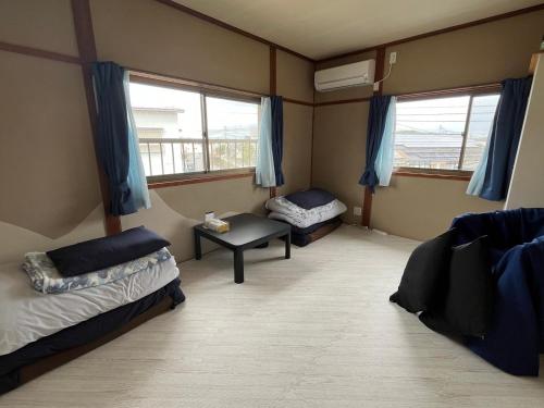 a room with two beds and a table and windows at ばんぶ〜ハウス(BambooHouse) in Shimo-ōzu