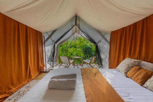 uma cama numa tenda com uma mesa e cadeiras em Camani Glamping em Karangasem