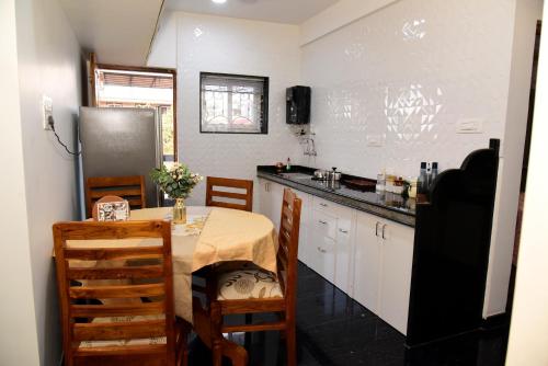 a small kitchen with a table and a refrigerator at Villa Elle L1 in Gandaulim