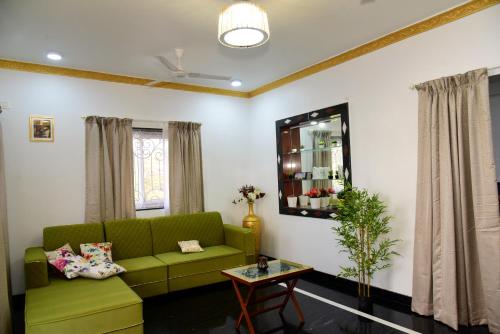 a living room with a green couch and a table at Villa Elle L1 in Gandaulim