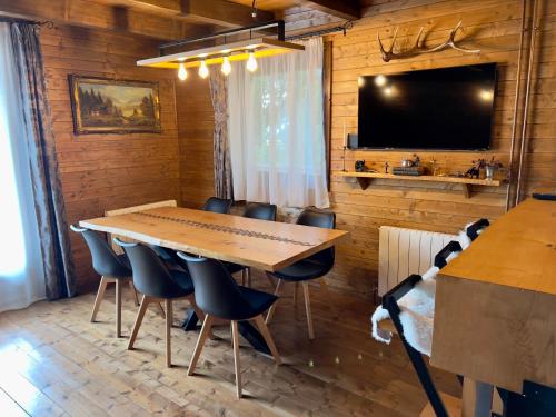 une salle à manger avec une table, des chaises et une télévision dans l'établissement Chalet A Baisoara - Cabana A-Frame la munte, à Băişoara