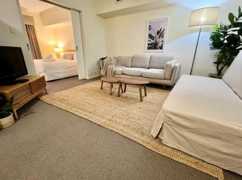 ein großes Wohnzimmer mit einem Sofa und einem TV in der Unterkunft Exceptional Apt in the heart of Perth City in Perth
