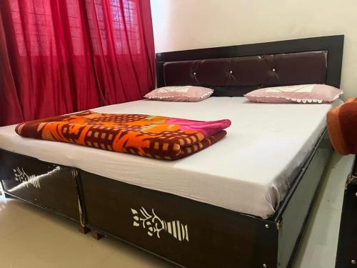 a bed with a black frame with a orange blanket on it at Hotel Rudraksh Inn , Barkot in Barkot