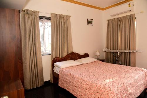 a bedroom with a bed and a window with curtains at Villa Elle L1 in Gandaulim