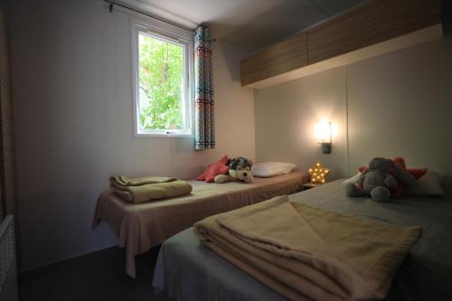 una habitación con 2 camas con animales de peluche. en Camping International & Spa 4*, en Hyères