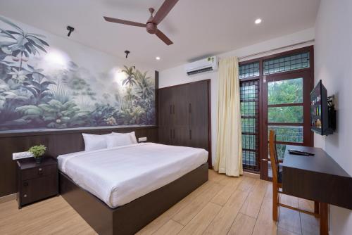 Dormitorio con cama, escritorio y pintura en Reach Homes, en Kochi